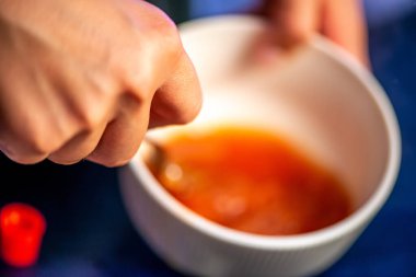 Domates ezmesini karıştıran, ev yemeğinin sıcaklığını ve leziz bir yemeğin dokusunu yakalayan bir kadının doğal mutfak sahnesi..