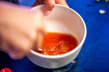 Domates ezmesini karıştıran, ev yemeğinin sıcaklığını ve leziz bir yemeğin dokusunu yakalayan bir kadının doğal mutfak sahnesi..