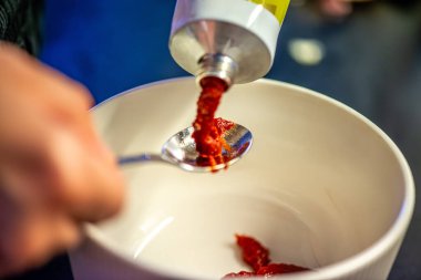 Domates ezmesini karıştıran, ev yemeğinin sıcaklığını ve leziz bir yemeğin dokusunu yakalayan bir kadının doğal mutfak sahnesi..