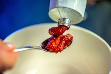 Domates ezmesini karıştıran, ev yemeğinin sıcaklığını ve leziz bir yemeğin dokusunu yakalayan bir kadının doğal mutfak sahnesi..