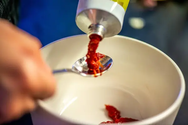 Domates ezmesini karıştıran, ev yemeğinin sıcaklığını ve leziz bir yemeğin dokusunu yakalayan bir kadının doğal mutfak sahnesi..