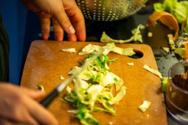 Salatalık, marul ve diğer sebzeleri dilimleyen bir kadının ev yapımı salatanın tazeliğini ve sağlığını yakaladığı canlı bir mutfak sahnesi..