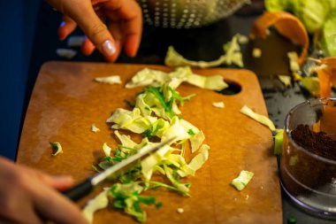 Salatalık, marul ve diğer sebzeleri dilimleyen bir kadının ev yapımı salatanın tazeliğini ve sağlığını yakaladığı canlı bir mutfak sahnesi..