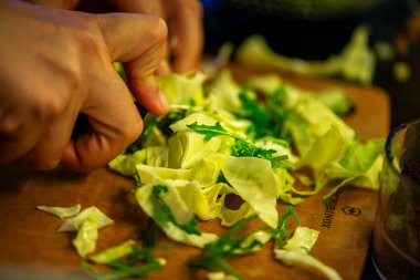Salatalık, marul ve diğer sebzeleri dilimleyen bir kadının ev yapımı salatanın tazeliğini ve sağlığını yakaladığı canlı bir mutfak sahnesi..