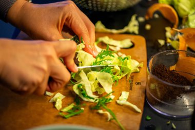 Salatalık, marul ve diğer sebzeleri dilimleyen bir kadının ev yapımı salatanın tazeliğini ve sağlığını yakaladığı canlı bir mutfak sahnesi..