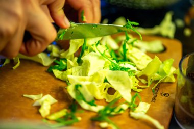 Salatalık, marul ve diğer sebzeleri dilimleyen bir kadının ev yapımı salatanın tazeliğini ve sağlığını yakaladığı canlı bir mutfak sahnesi..
