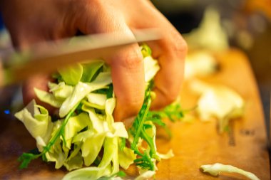 Salatalık, marul ve diğer sebzeleri dilimleyen bir kadının ev yapımı salatanın tazeliğini ve sağlığını yakaladığı canlı bir mutfak sahnesi..