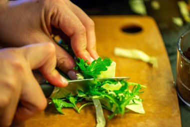 Salatalık, marul ve diğer sebzeleri dilimleyen bir kadının ev yapımı salatanın tazeliğini ve sağlığını yakaladığı canlı bir mutfak sahnesi..