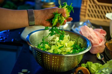 Salatalık, marul ve diğer sebzeleri dilimleyen bir kadının ev yapımı salatanın tazeliğini ve sağlığını yakaladığı canlı bir mutfak sahnesi..