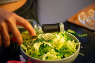 Canlı bir makro fotoğraf taze bir limonu dilimleyen ve meyve suyunu renkli bir salatanın üzerine sıkan bir kadını yakalıyor, narenciye dokusunu ve mutfak faaliyetlerindeki tazeliği vurguluyor..