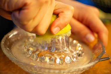 Canlı bir makro fotoğraf taze bir limonu dilimleyen ve meyve suyunu renkli bir salatanın üzerine sıkan bir kadını yakalıyor, narenciye dokusunu ve mutfak faaliyetlerindeki tazeliği vurguluyor..