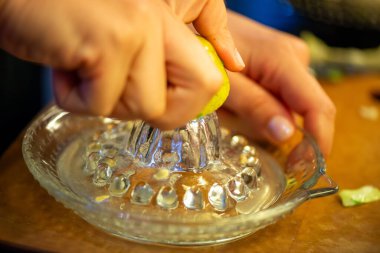 Canlı bir makro fotoğraf taze bir limonu dilimleyen ve meyve suyunu renkli bir salatanın üzerine sıkan bir kadını yakalıyor, narenciye dokusunu ve mutfak faaliyetlerindeki tazeliği vurguluyor..