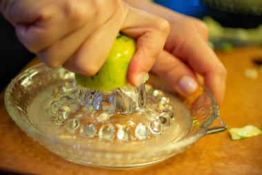 Canlı bir makro fotoğraf taze bir limonu dilimleyen ve meyve suyunu renkli bir salatanın üzerine sıkan bir kadını yakalıyor, narenciye dokusunu ve mutfak faaliyetlerindeki tazeliği vurguluyor..