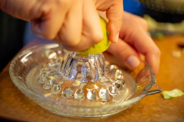 Canlı bir makro fotoğraf taze bir limonu dilimleyen ve meyve suyunu renkli bir salatanın üzerine sıkan bir kadını yakalıyor, narenciye dokusunu ve mutfak faaliyetlerindeki tazeliği vurguluyor..