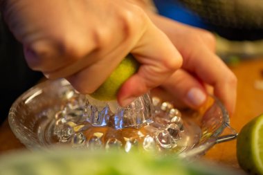 Canlı bir makro fotoğraf taze bir limonu dilimleyen ve meyve suyunu renkli bir salatanın üzerine sıkan bir kadını yakalıyor, narenciye dokusunu ve mutfak faaliyetlerindeki tazeliği vurguluyor..