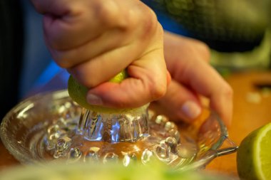 Canlı bir makro fotoğraf taze bir limonu dilimleyen ve meyve suyunu renkli bir salatanın üzerine sıkan bir kadını yakalıyor, narenciye dokusunu ve mutfak faaliyetlerindeki tazeliği vurguluyor..