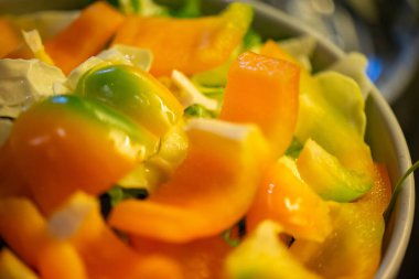 Salatalık, marul ve diğer sebzeleri dilimleyen bir kadının ev yapımı salatanın tazeliğini ve sağlığını yakaladığı canlı bir mutfak sahnesi..