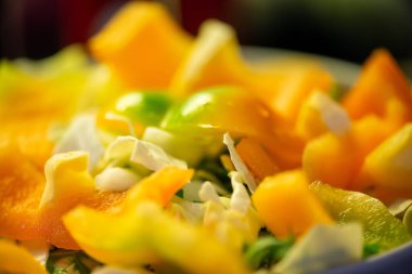 Salatalık, marul ve diğer sebzeleri dilimleyen bir kadının ev yapımı salatanın tazeliğini ve sağlığını yakaladığı canlı bir mutfak sahnesi..