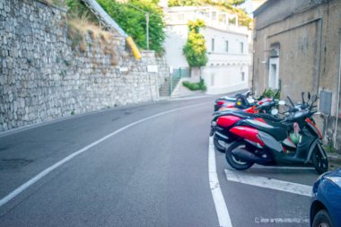 Dar kaldırım taşları, renkli Akdeniz binaları, çiçeklerle dolu balkonlar ve yerel hayatın yer aldığı Amalfi Sahili 'nden pitoresk bir sokak manzarası.