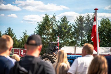 Aarhus, Danimarka. 16 Ağustos 2025 Güçlü makinelerin neşeli festival kalabalığından önce ağır topları çamura sürüklediği bir yarışma..