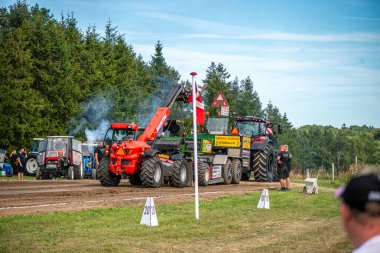 Aarhus, Danimarka. 16 Ağustos 2025 Güçlü makinelerin neşeli festival kalabalığından önce ağır topları çamura sürüklediği bir yarışma..