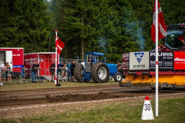 Aarhus, Danimarka. 16 Ağustos 2025 Güçlü makinelerin neşeli festival kalabalığından önce ağır topları çamura sürüklediği bir yarışma..