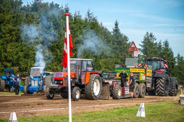 Aarhus, Danimarka. 16 Ağustos 2025 Güçlü makinelerin neşeli festival kalabalığından önce ağır topları çamura sürüklediği bir yarışma..