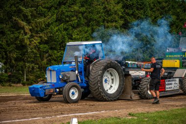 Aarhus, Danimarka. 16 Ağustos 2025 Güçlü makinelerin neşeli festival kalabalığından önce ağır topları çamura sürüklediği bir yarışma..