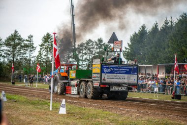 Aarhus, Danimarka. 16 Ağustos 2025 Güçlü makinelerin neşeli festival kalabalığından önce ağır topları çamura sürüklediği bir yarışma..