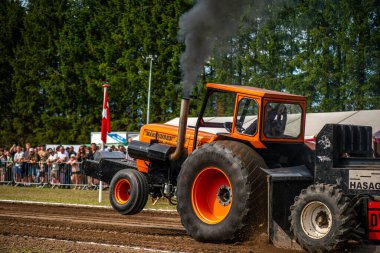 Aarhus, Danimarka. 16 Ağustos 2025 Güçlü makinelerin neşeli festival kalabalığından önce ağır topları çamura sürüklediği bir yarışma..