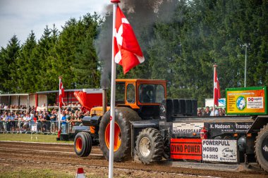 Aarhus, Danimarka. 16 Ağustos 2025 Güçlü makinelerin neşeli festival kalabalığından önce ağır topları çamura sürüklediği bir yarışma..