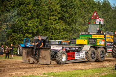 Aarhus, Danimarka. 16 Ağustos 2025 Güçlü makinelerin neşeli festival kalabalığından önce ağır topları çamura sürüklediği bir yarışma..