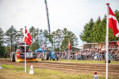 Aarhus, Danimarka. 16 Ağustos 2025 Güçlü makinelerin neşeli festival kalabalığından önce ağır topları çamura sürüklediği bir yarışma..