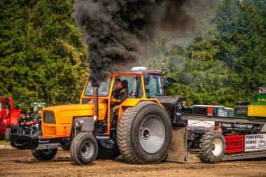 Aarhus, Danimarka. 16 Ağustos 2025 Güçlü makinelerin neşeli festival kalabalığından önce ağır topları çamura sürüklediği bir yarışma..