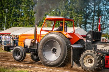 Aarhus, Danimarka. 16 Ağustos 2025 Güçlü makinelerin neşeli festival kalabalığından önce ağır topları çamura sürüklediği bir yarışma..