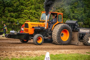 Aarhus, Danimarka. 16 Ağustos 2025 Güçlü makinelerin neşeli festival kalabalığından önce ağır topları çamura sürüklediği bir yarışma..