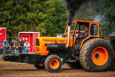 Aarhus, Danimarka. 16 Ağustos 2025 Güçlü makinelerin neşeli festival kalabalığından önce ağır topları çamura sürüklediği bir yarışma..
