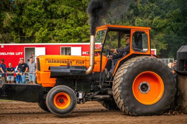 Aarhus, Danimarka. 16 Ağustos 2025 Güçlü makinelerin neşeli festival kalabalığından önce ağır topları çamura sürüklediği bir yarışma..