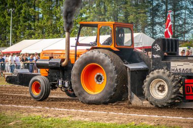 Aarhus, Danimarka. 16 Ağustos 2025 Güçlü makinelerin neşeli festival kalabalığından önce ağır topları çamura sürüklediği bir yarışma..