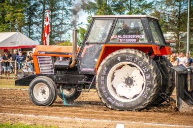 Aarhus, Danimarka. 16 Ağustos 2025 Güçlü makinelerin neşeli festival kalabalığından önce ağır topları çamura sürüklediği bir yarışma..