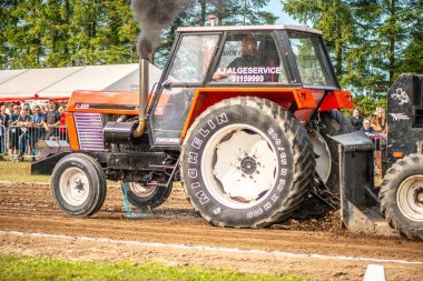 Aarhus, Danimarka. 16 Ağustos 2025 Güçlü makinelerin neşeli festival kalabalığından önce ağır topları çamura sürüklediği bir yarışma..