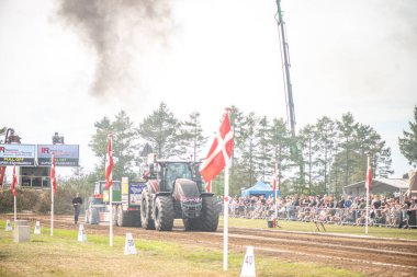 Aarhus, Danimarka. 16 Ağustos 2025 Güçlü makinelerin neşeli festival kalabalığından önce ağır topları çamura sürüklediği bir yarışma..