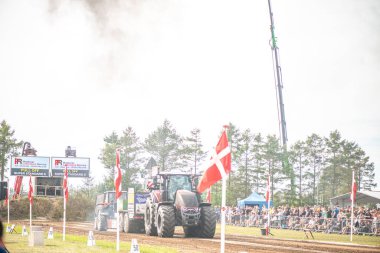 Aarhus, Danimarka. 16 Ağustos 2025 Güçlü makinelerin neşeli festival kalabalığından önce ağır topları çamura sürüklediği bir yarışma..