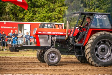Aarhus, Danimarka. 16 Ağustos 2025 Güçlü makinelerin neşeli festival kalabalığından önce ağır topları çamura sürüklediği bir yarışma..