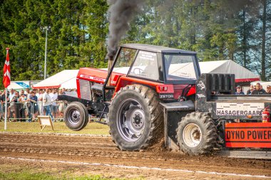 Aarhus, Danimarka. 16 Ağustos 2025 Güçlü makinelerin neşeli festival kalabalığından önce ağır topları çamura sürüklediği bir yarışma..