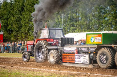 Aarhus, Danimarka. 16 Ağustos 2025 Güçlü makinelerin neşeli festival kalabalığından önce ağır topları çamura sürüklediği bir yarışma..