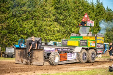 Aarhus, Danimarka. 16 Ağustos 2025 Güçlü makinelerin neşeli festival kalabalığından önce ağır topları çamura sürüklediği bir yarışma..
