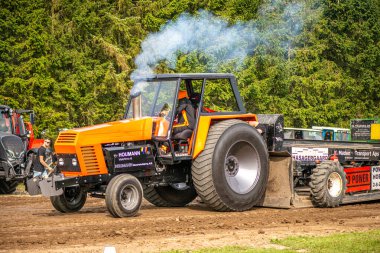 Aarhus, Danimarka. 16 Ağustos 2025 Güçlü makinelerin neşeli festival kalabalığından önce ağır topları çamura sürüklediği bir yarışma..