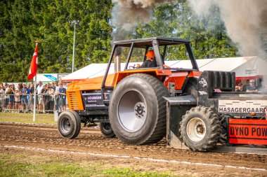 Aarhus, Danimarka. 16 Ağustos 2025 Güçlü makinelerin neşeli festival kalabalığından önce ağır topları çamura sürüklediği bir yarışma..