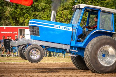 Aarhus, Danimarka. 16 Ağustos 2025 Güçlü makinelerin neşeli festival kalabalığından önce ağır topları çamura sürüklediği bir yarışma..